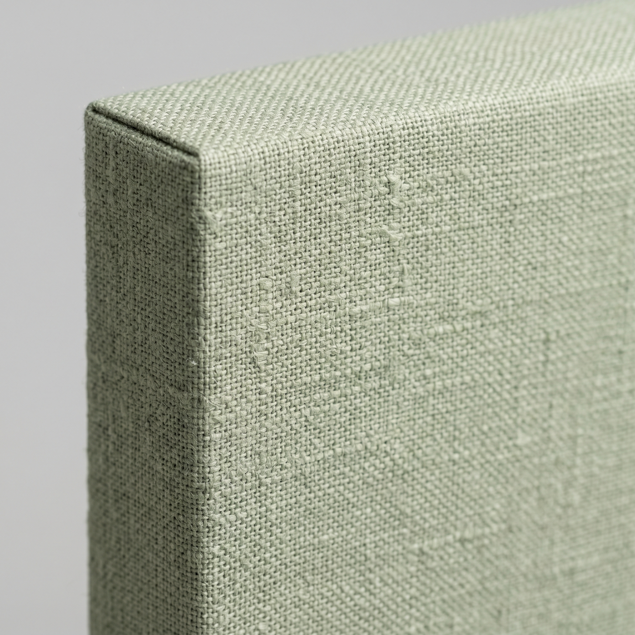 Close-up of a premium sage green fabric-wrapped acoustic panel with clean aluminium frame